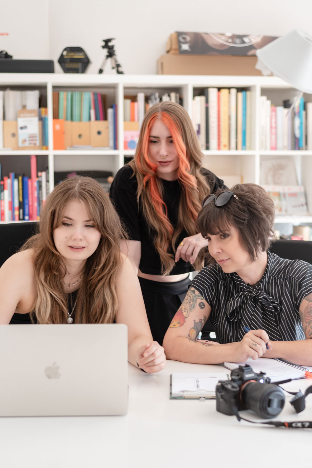 Drei Frauen des Marketing-Gilde-Teams arbeiten gemeinsam an einem Laptop in einem kreativen Büro – zuständig für Webentwicklung, Content Creation, Grafikdesign und Social Media Marketing.